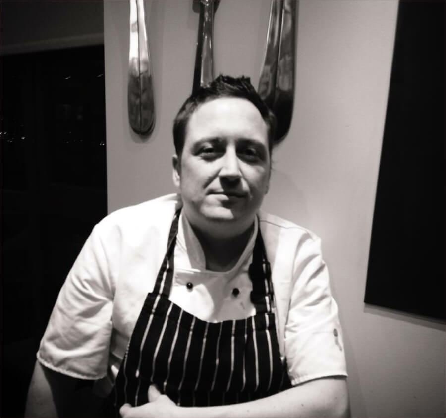 Ryan Tomkins in chef&rsquo;s whites and a striped apron